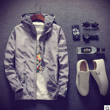 Gray hooded jacket with colorful inner lining, white sneakers, and accessories on a dark surface.