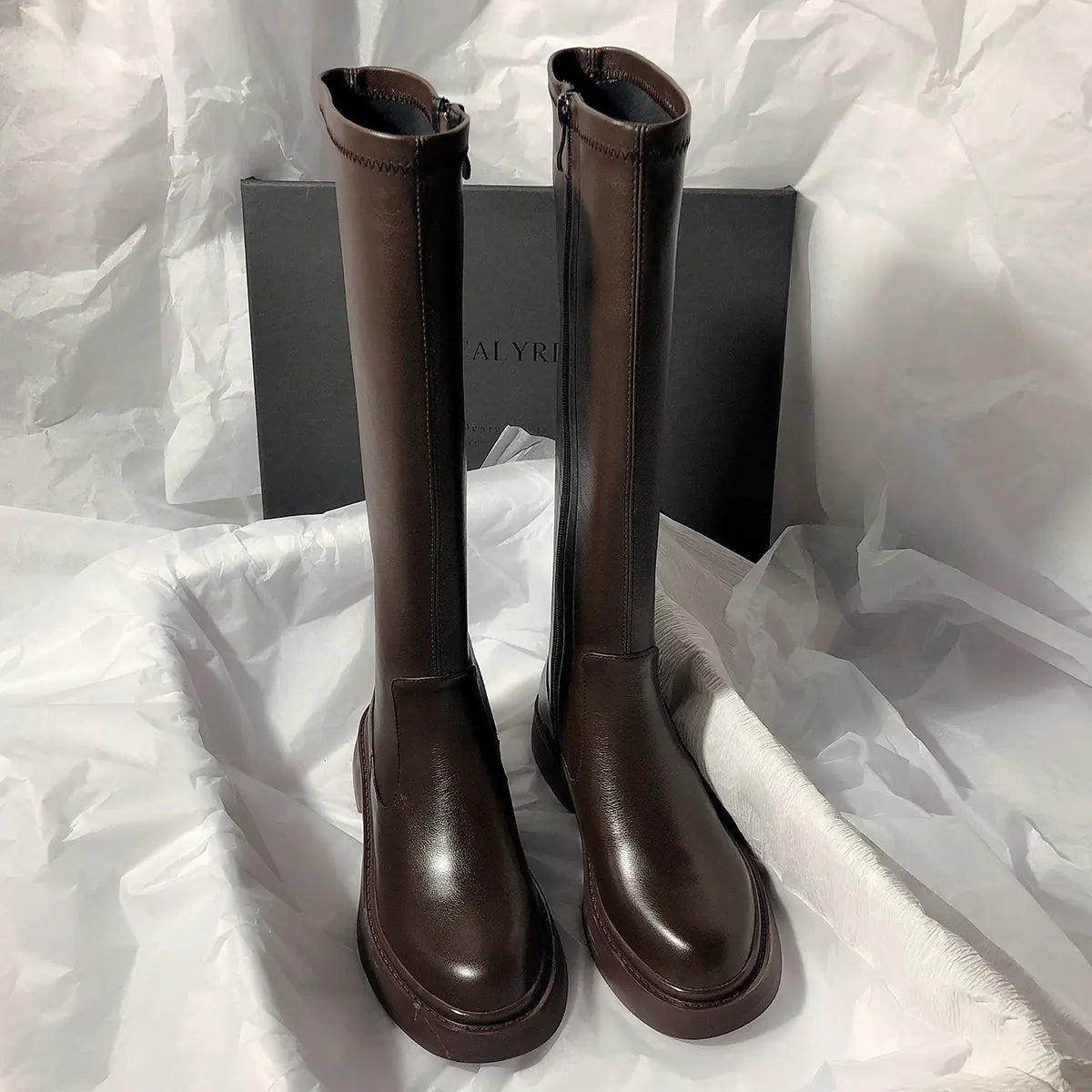 Pair of brown knee-high boots on a white fabric background