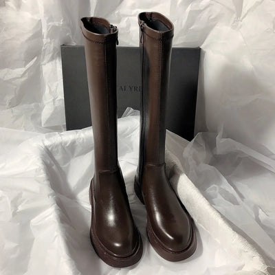 Pair of brown knee-high boots on a white fabric background