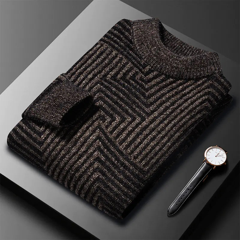 Folded black patterned sweater on a gray surface with a watch beside it