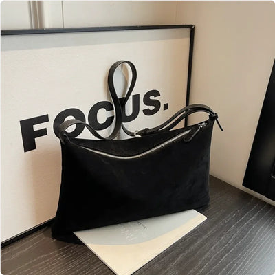 Black handbag on a surface with a 'FOCUS.' sign in the background