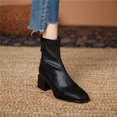 Black ankle boot worn with blue jeans on a textured surface