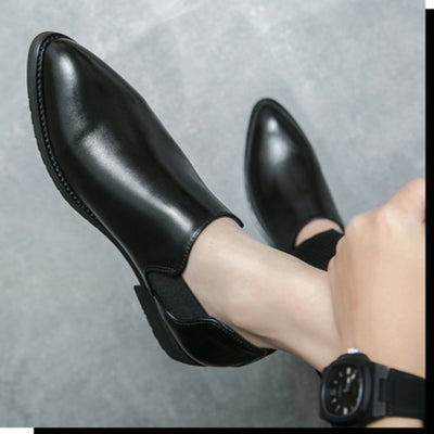 Black leather shoes worn on a gray background