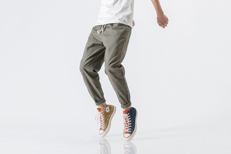 Person wearing green pants and colorful sneakers on a white background