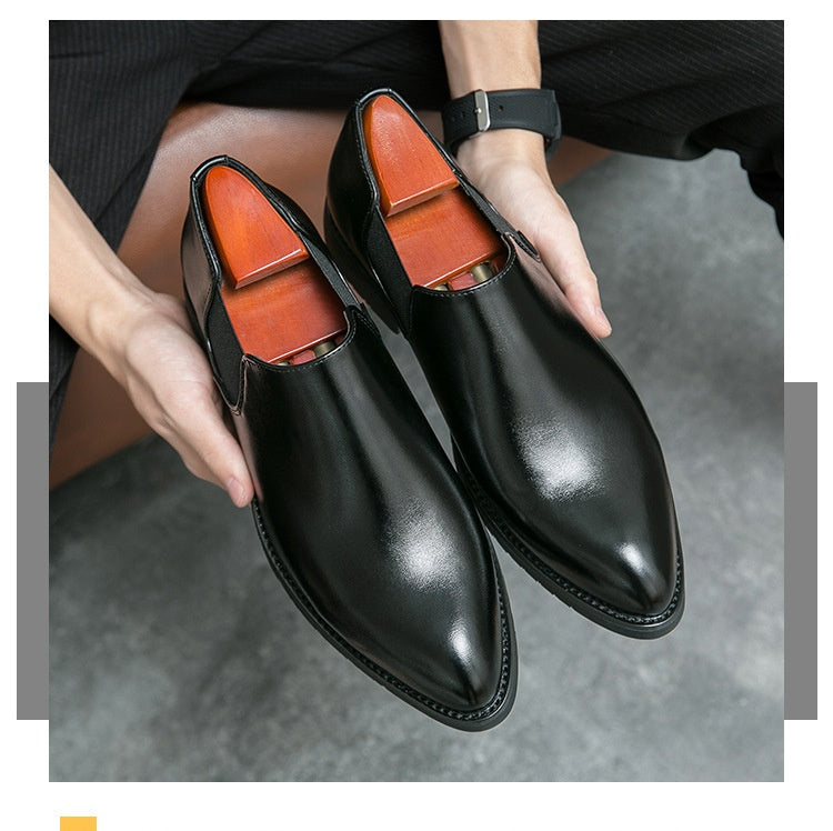 Black dress shoes with brown lining held by a person on a gray surface