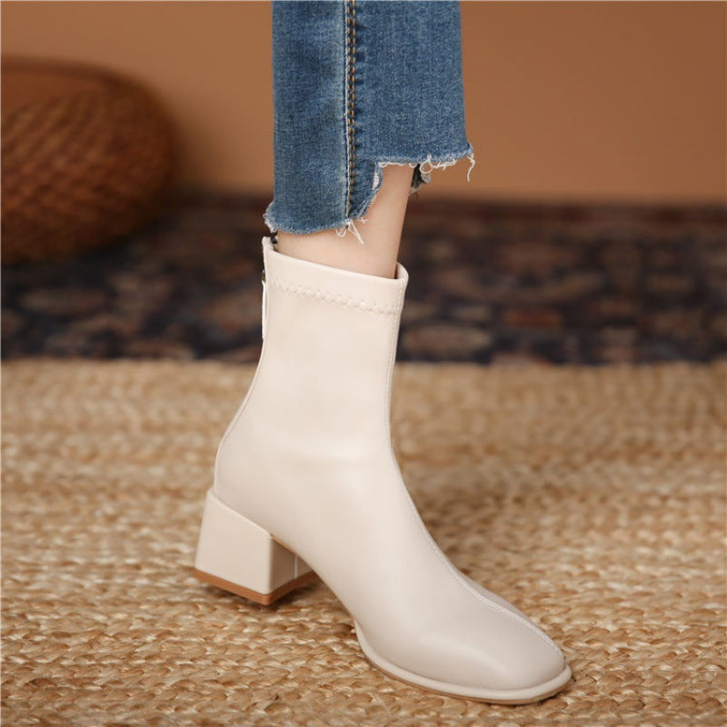 Beige ankle boot worn with blue jeans on a textured surface