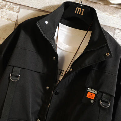 Black jacket with a white shirt underneath on a hanger against a textured wall.