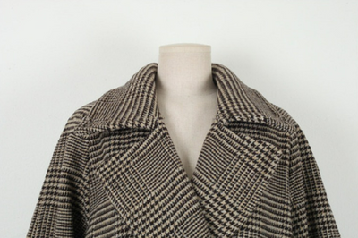 Houndstooth patterned coat on a mannequin against a white background