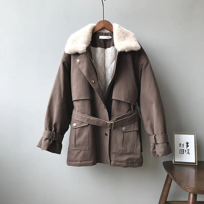 Brown coat with fur collar on a hanger against a gray wall.