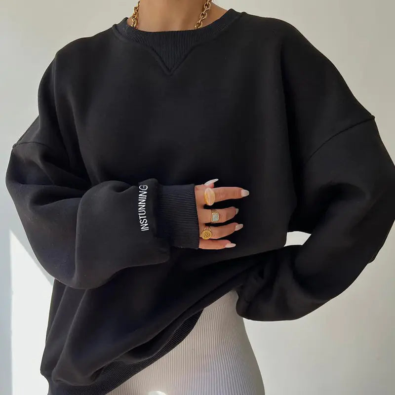 Black oversized sweatshirt with 'INSTUNNING' text on sleeve, worn by a person.