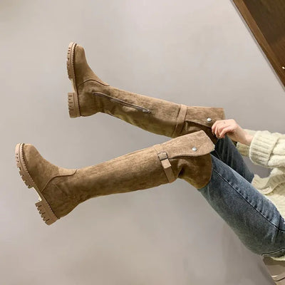Tan knee-high boots being worn with a neutral background