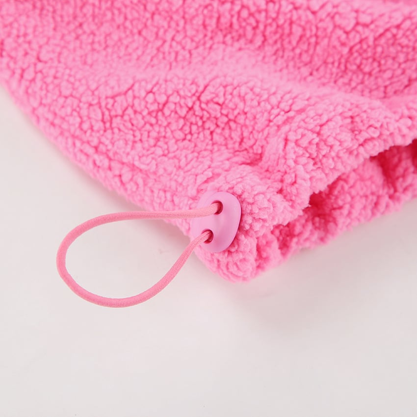 Pink fluffy towel with a pink rubber band on a light pink background