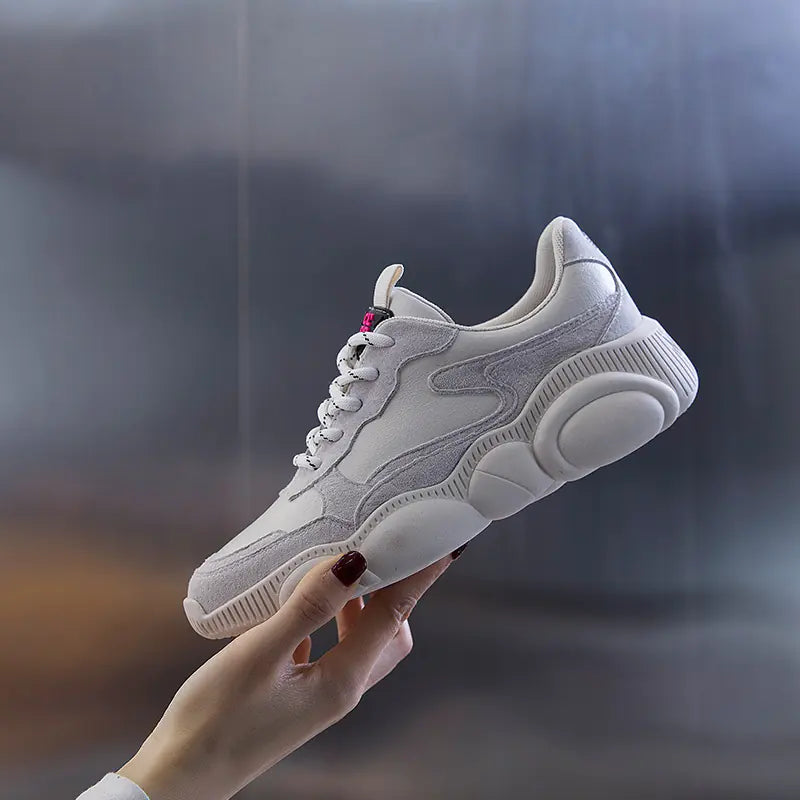 White sneaker held by a hand against a blurred background