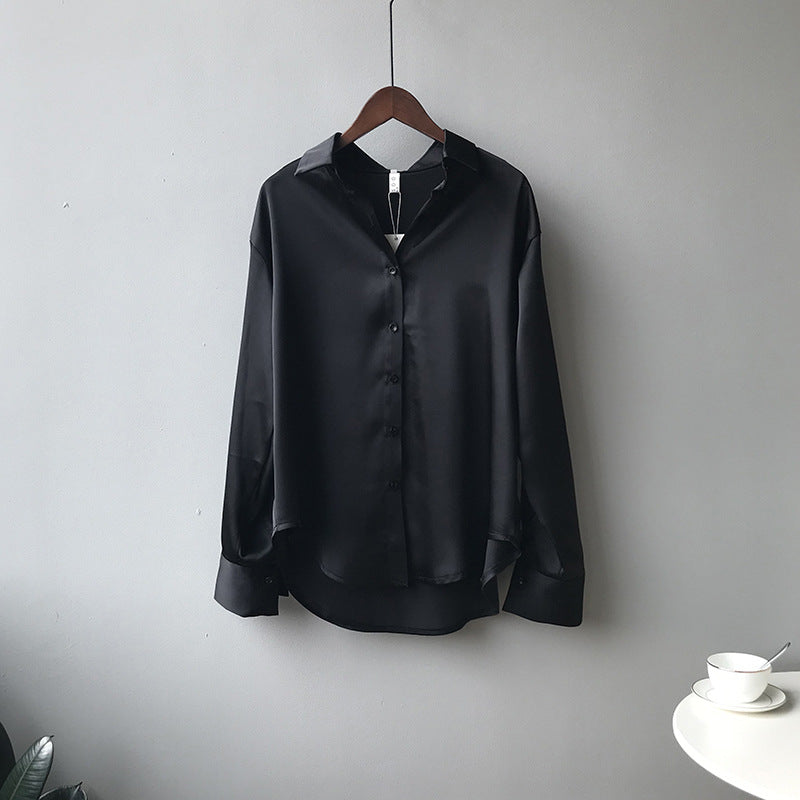 Black satin shirt on a hanger against a plain background