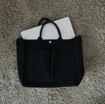 Black tote bag with a white laptop on a textured surface