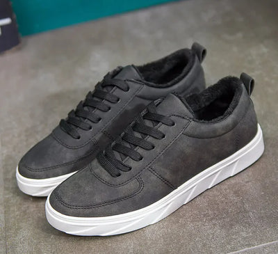 Pair of gray sneakers with white soles on a gray surface