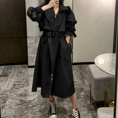 Person wearing a black trench coat in an indoor setting