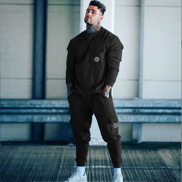 Man wearing a dark brown tracksuit with a logo in an indoor setting