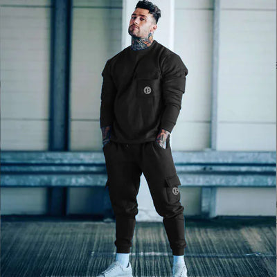 Man wearing a dark brown tracksuit with a logo in an indoor setting