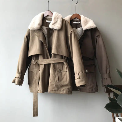 Two brown jackets with fur collars hanging on a white wall.