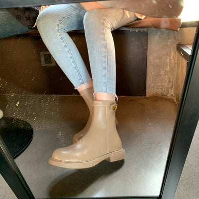Person wearing beige boots and light blue jeans sitting on a chair.
