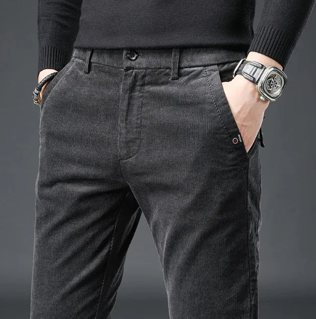 Person wearing dark gray corduroy pants with a plain background