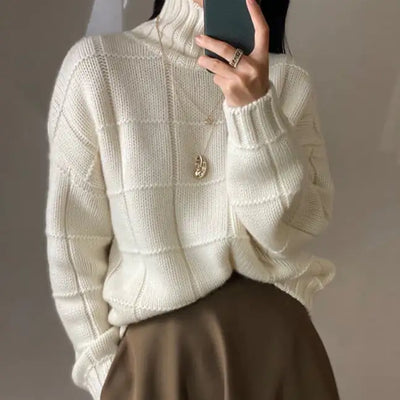Person wearing a white textured sweater with a plain background