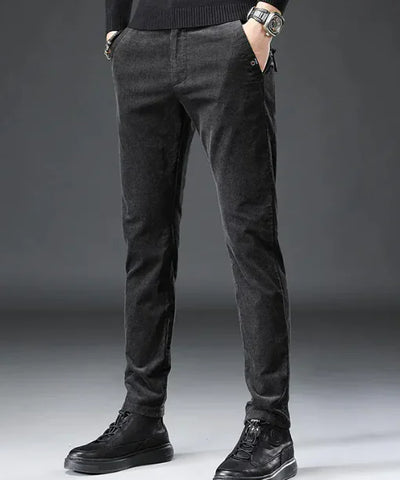 Person wearing dark gray pants and black shoes on a gray background
