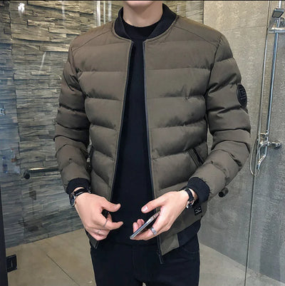 Person wearing a brown puffer jacket holding a phone in a bathroom.