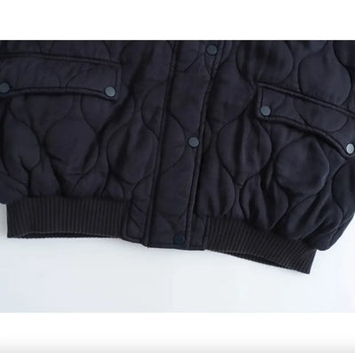 Black quilted jacket on a white background