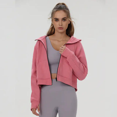 Woman wearing a pink hoodie and gray leggings on a white background