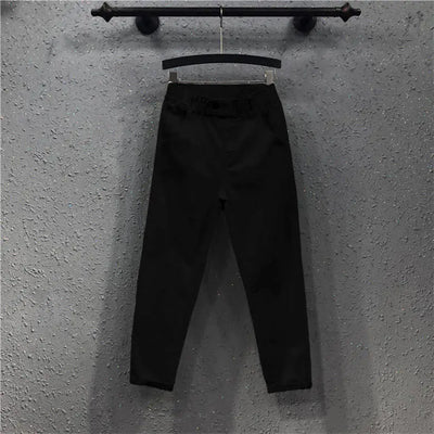 Black pants hanging on a hook against a gray wall