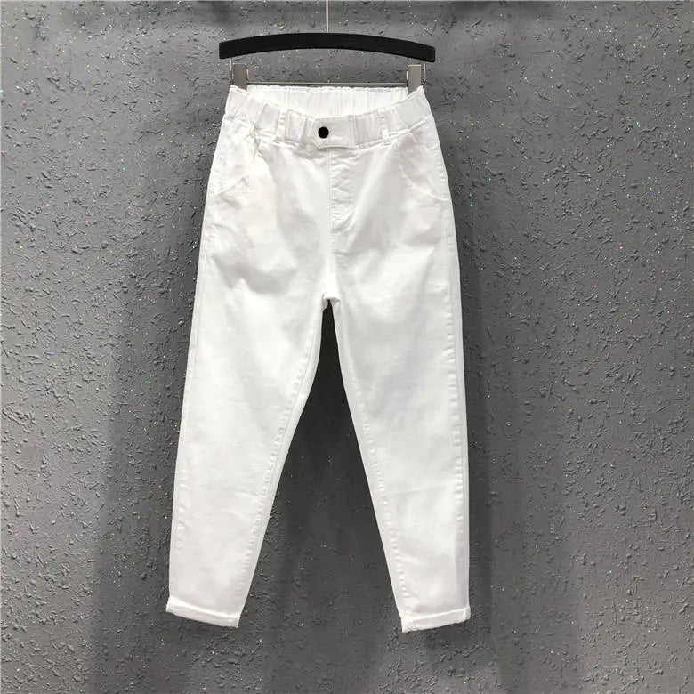 White jeans hanging on a hanger against a gray wall