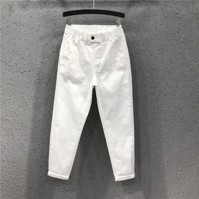 White jeans hanging on a hanger against a gray wall