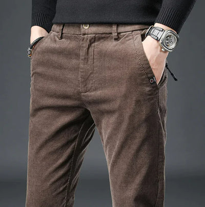 Brown corduroy pants worn by a person on a gray background