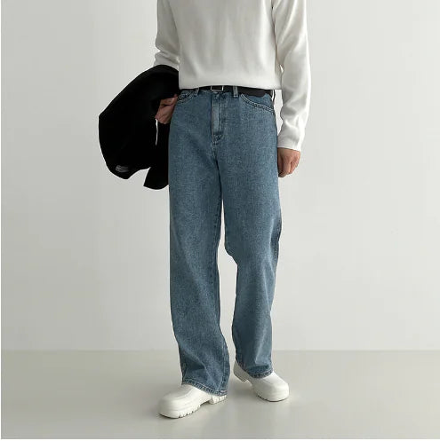 Person wearing blue jeans and a white long-sleeve shirt against a plain background