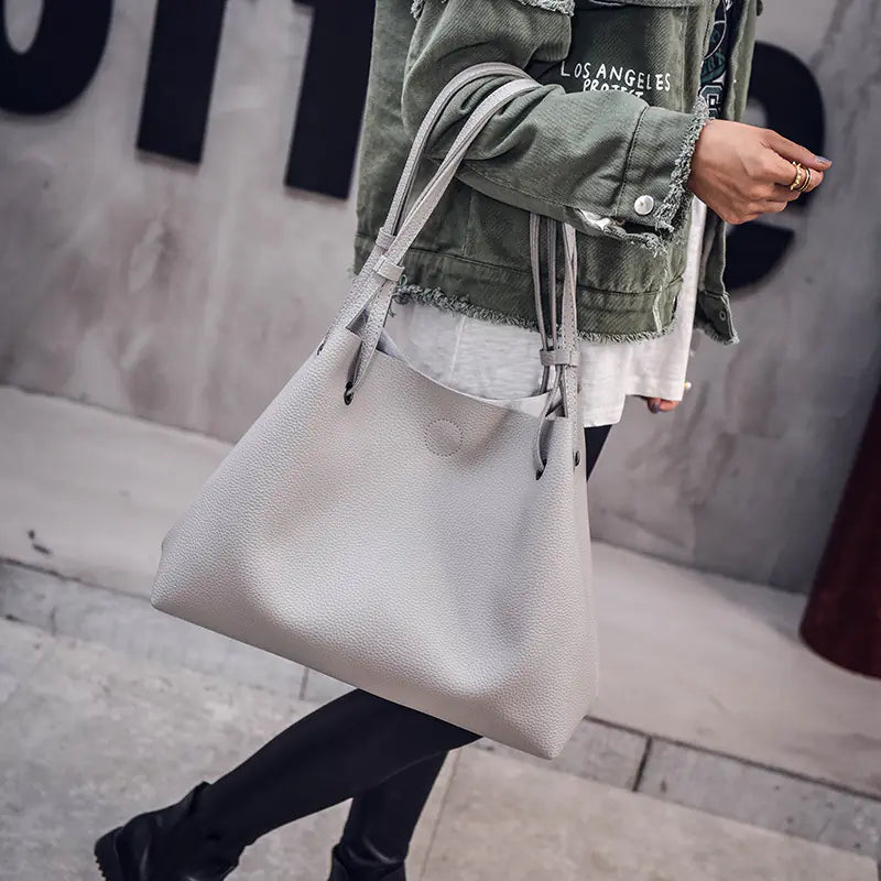 Person holding a light gray tote bag with a blurred background