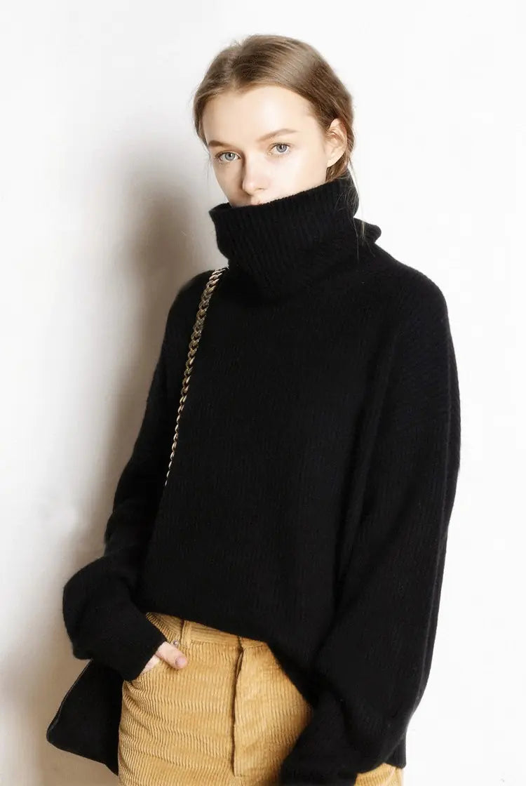 Person wearing a black turtleneck sweater and beige pants against a white background
