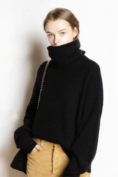 Person wearing a black turtleneck sweater and beige pants against a white background