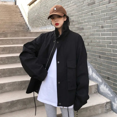Person wearing a black jacket and brown cap standing on steps against a brick wall.