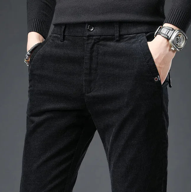 Person wearing black corduroy pants with a gray background