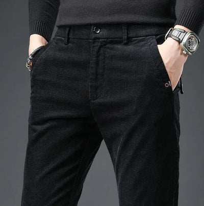 Person wearing black corduroy pants with a gray background