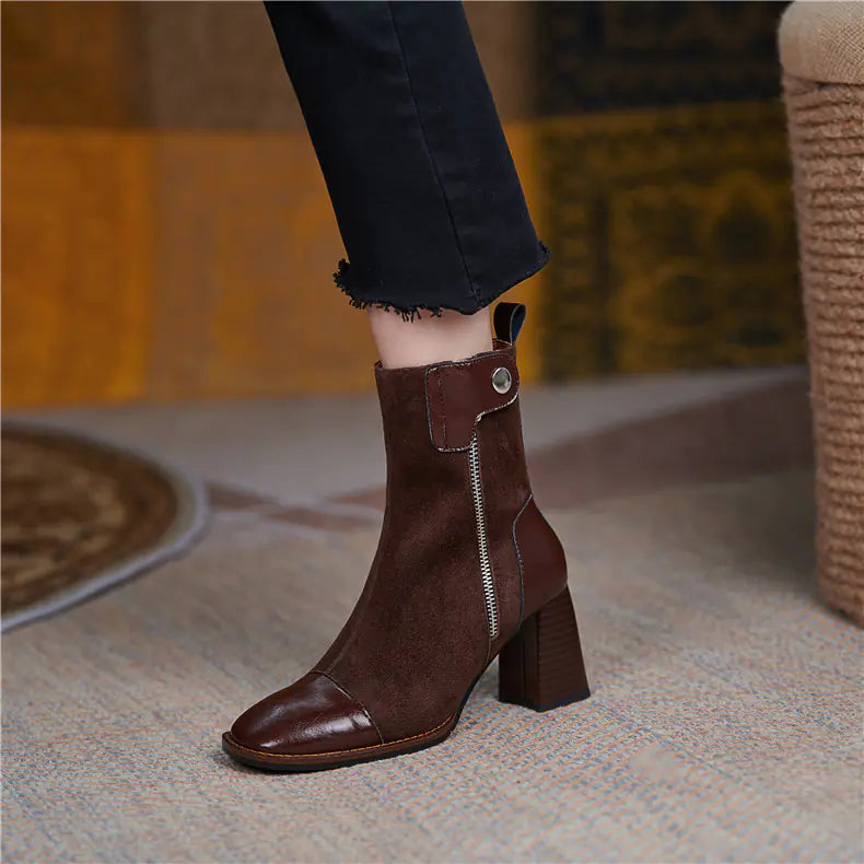 Brown ankle boot with a block heel worn by a person on a blurred indoor background