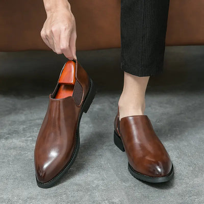 Brown leather shoes being worn on a gray floor with a blurred background