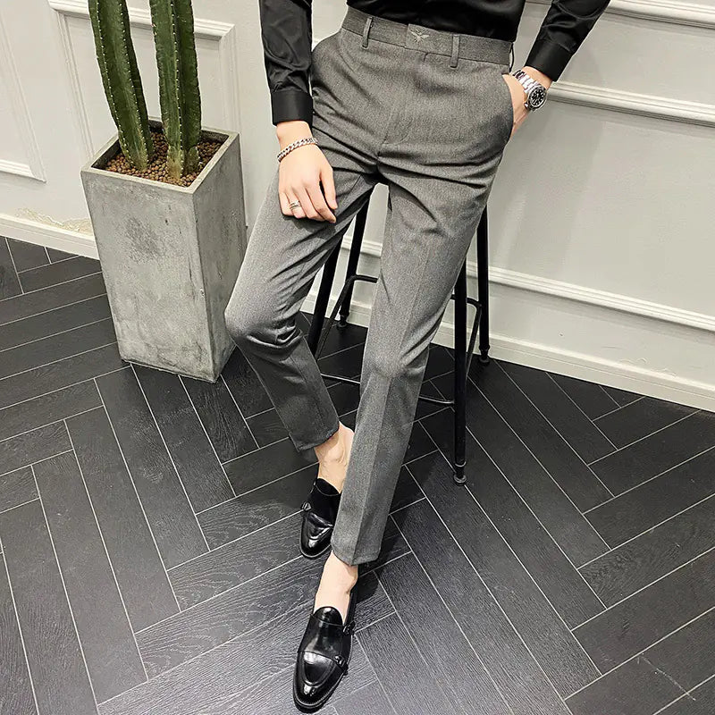 Person wearing gray pants and black shoes on a gray tiled floor.