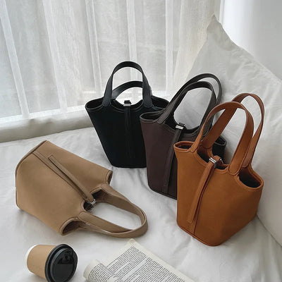 Four handbags in different colors on a light surface with a blurred background