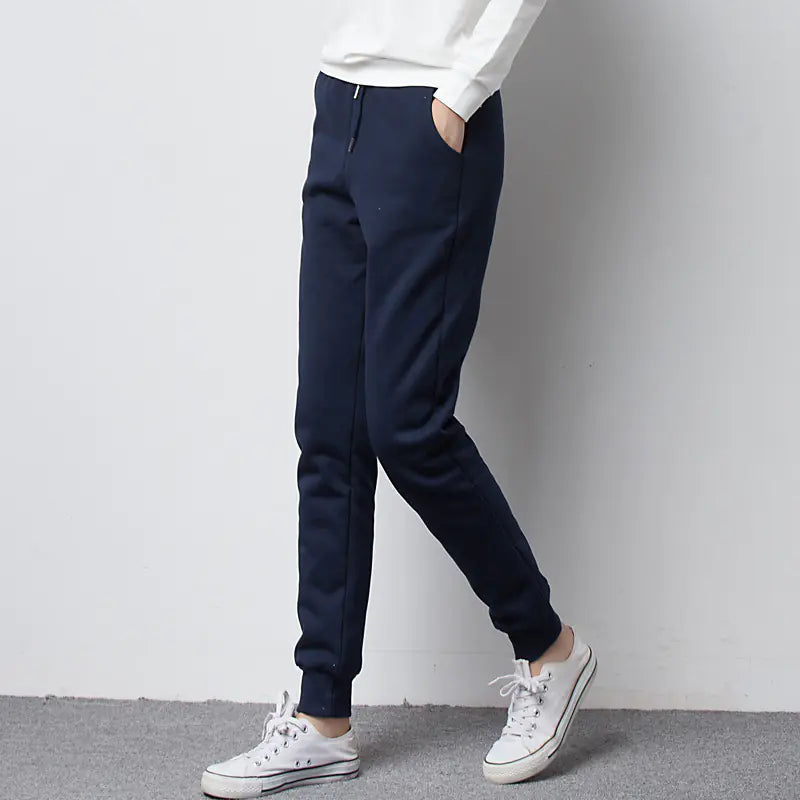 Person wearing navy jogger fleece pants and white sneakers on a plain background