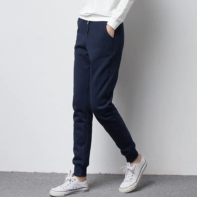 Person wearing navy jogger fleece pants and white sneakers on a plain background