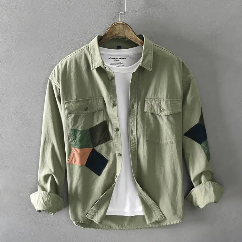 Green patchwork shirt on a hanger against a gray background