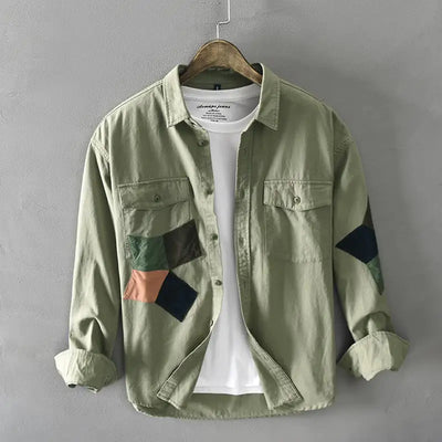 Green patchwork shirt on a hanger against a gray background